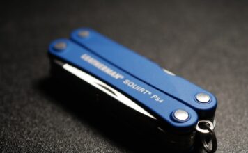 Multitoole do 100 zł – najlepsze opcje Multitool to jeden z podstawowych przedmiotów w zestawie survivalowym. na zdjęciu poręczny multitool Laethermana w kolorze niebieskim, złożony, leżący na czarnym stole.